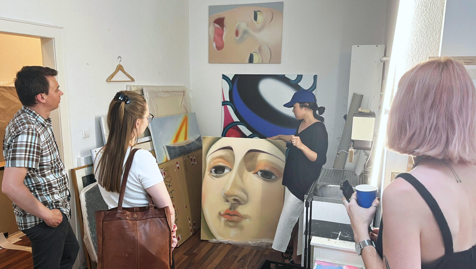 Gowoon erklärt einigen Menschen ihre Kunst in ihrem Atelier