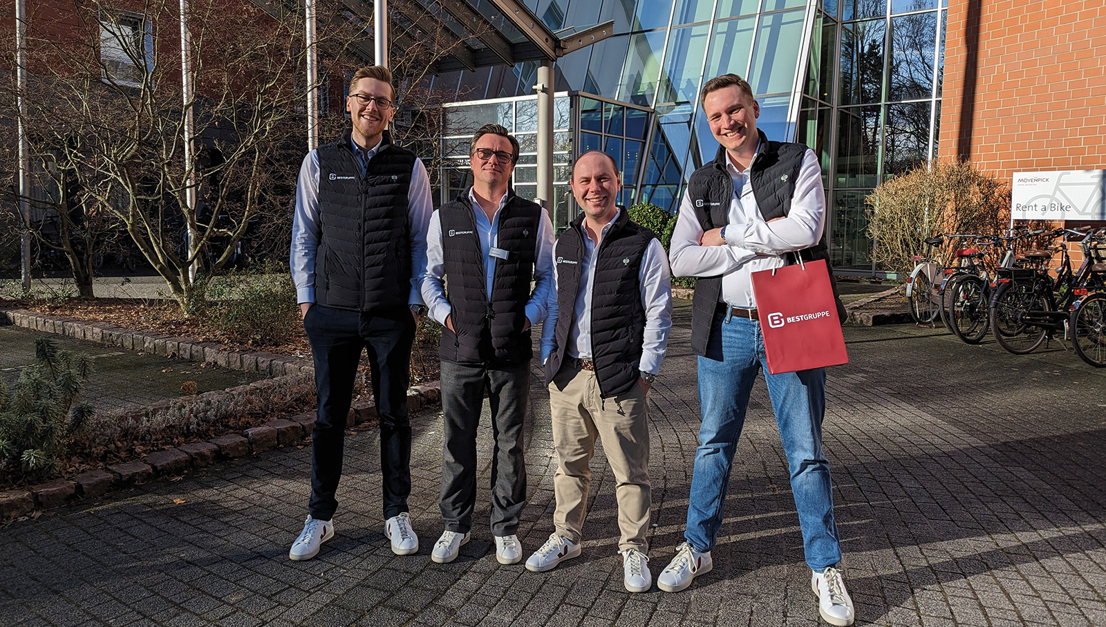 Vier Kollegen der BEST GRUPPE stehen vor einem Hotel, in dem eine Veranstaltung für Immobilienverwalter stattfindet.