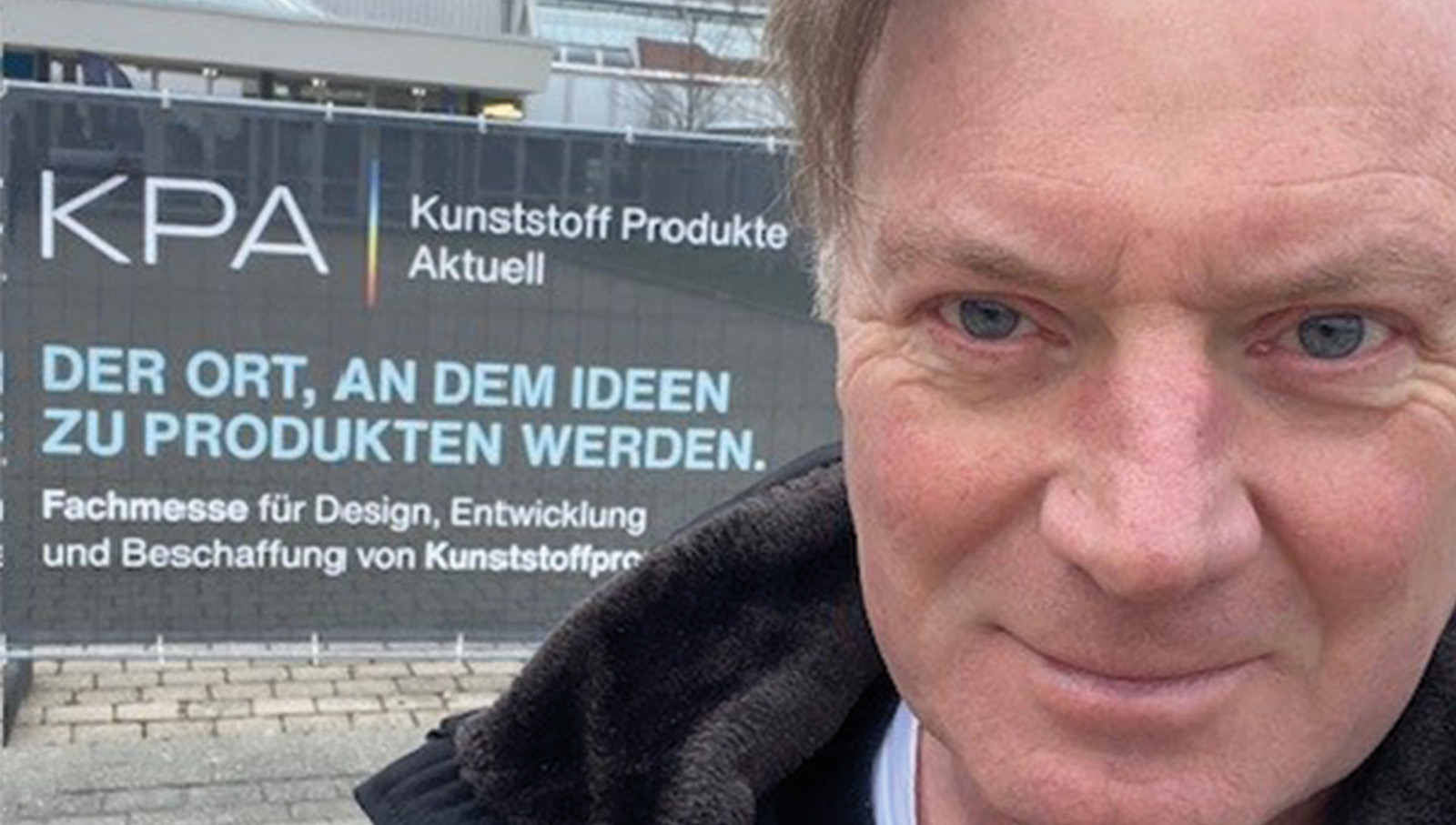 Geschäftsführer Stefan Peters lächelt vor dem Messeschild in die Kamera