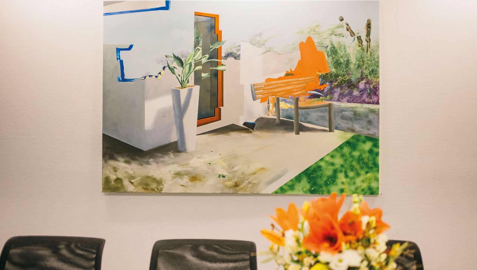 Bild des Künstlers an der Wand darunter ein paar Stühle und ein Blumenstrauß.