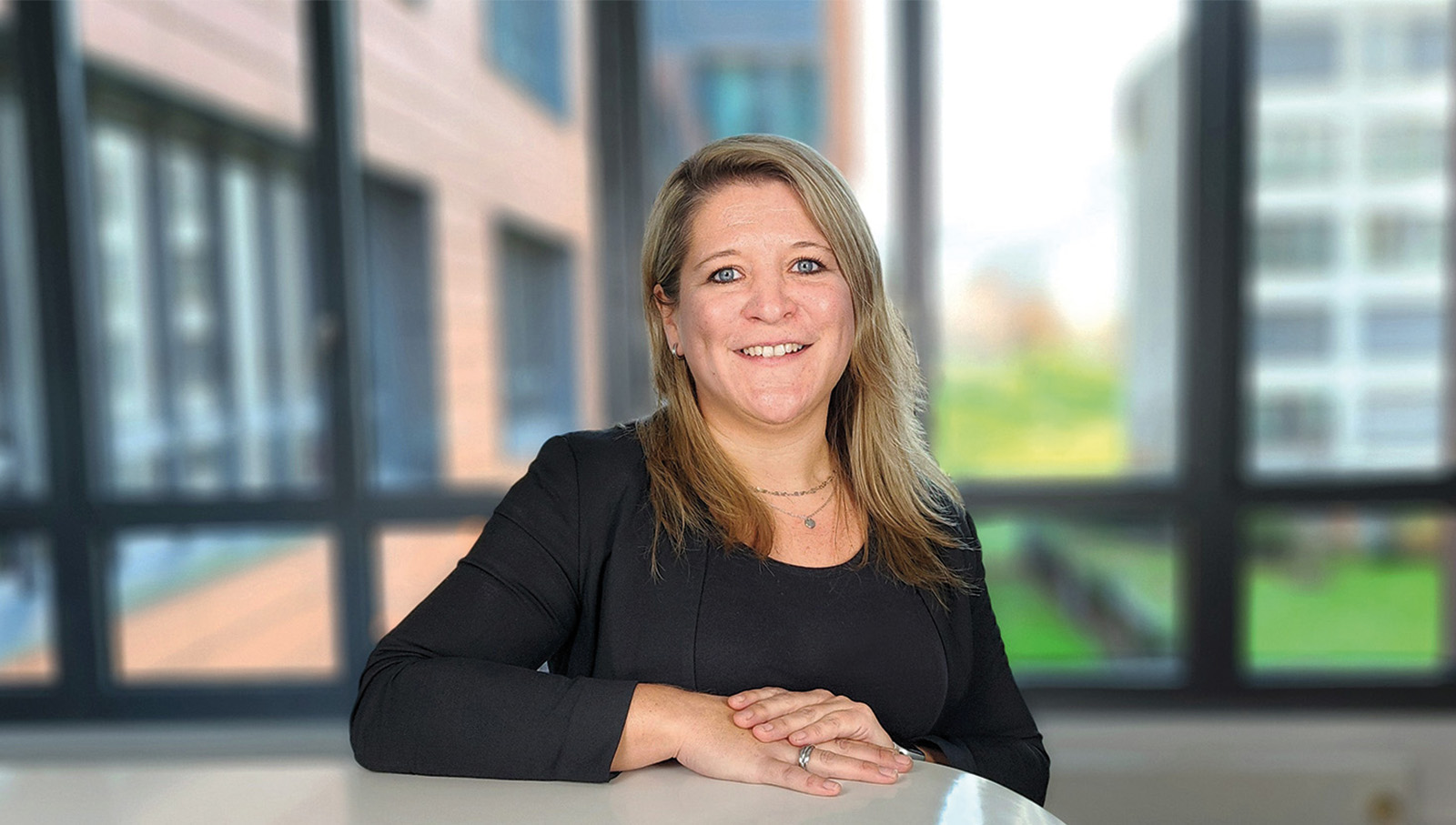 Nora Tjardes sitzt lächelnd an einem hohen Tisch