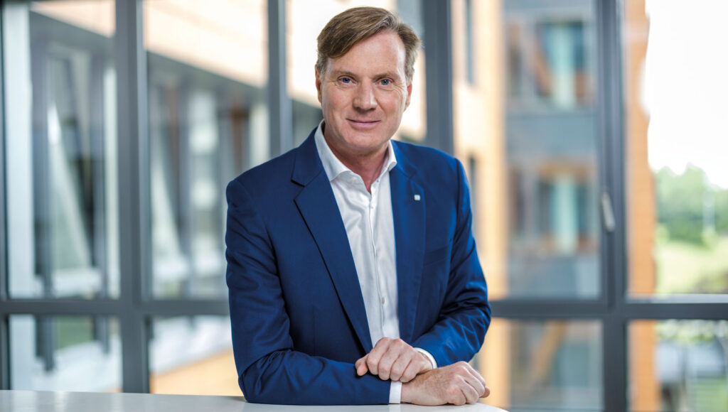 Stefan Petes lehnt sich lächelnd an einen hohen Tisch.