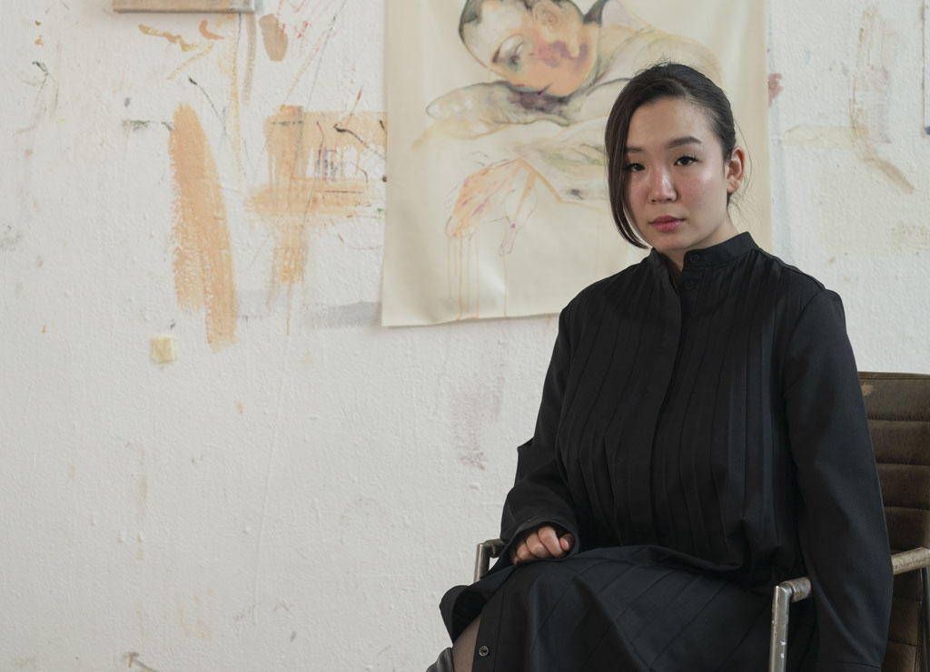 Juliana Paek sitzend vor Kunst an der Wand