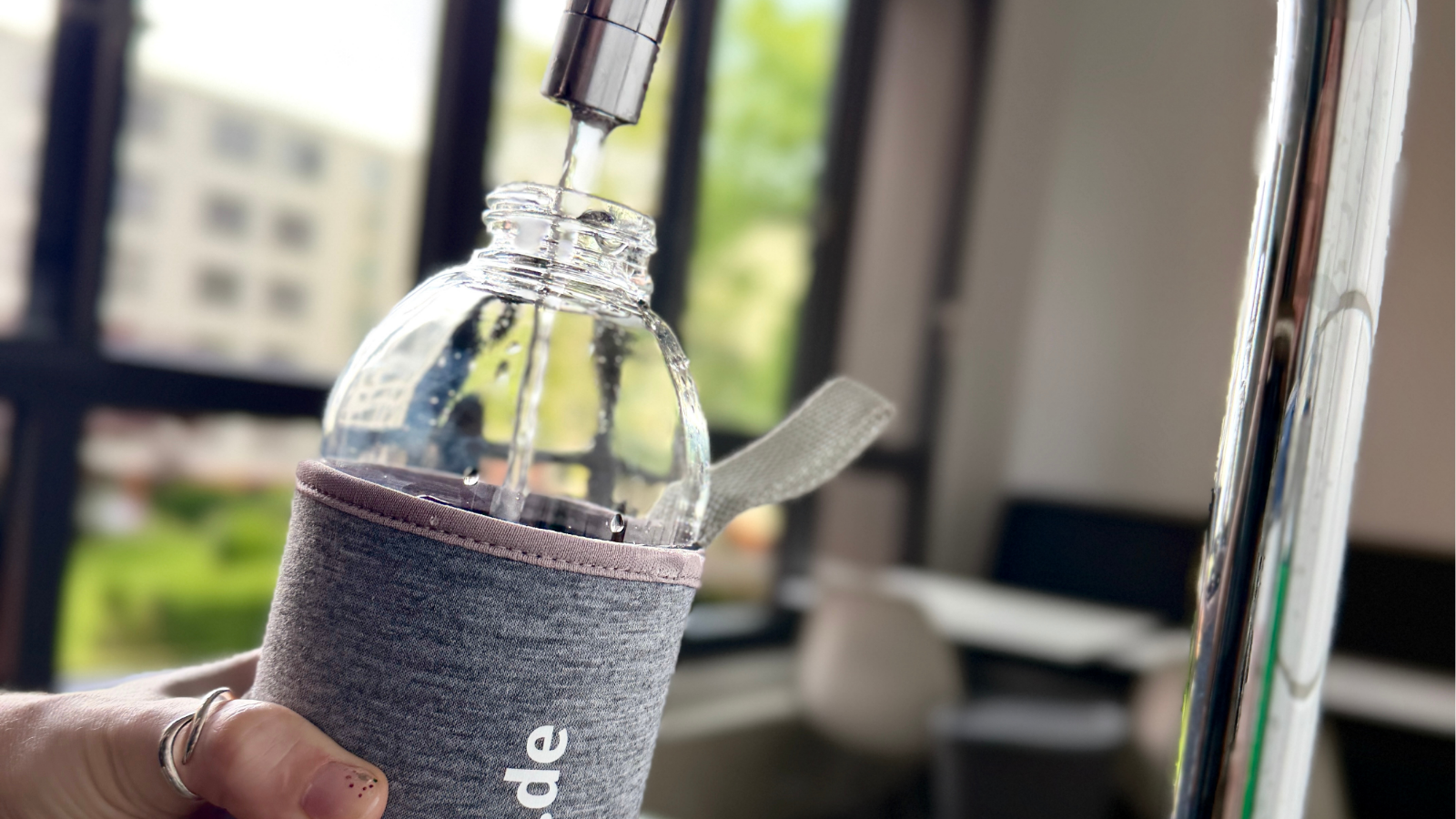 eine Flasche mit BEST GRUPPE Logo wird unter dem Hahn mit Wasser befüllt