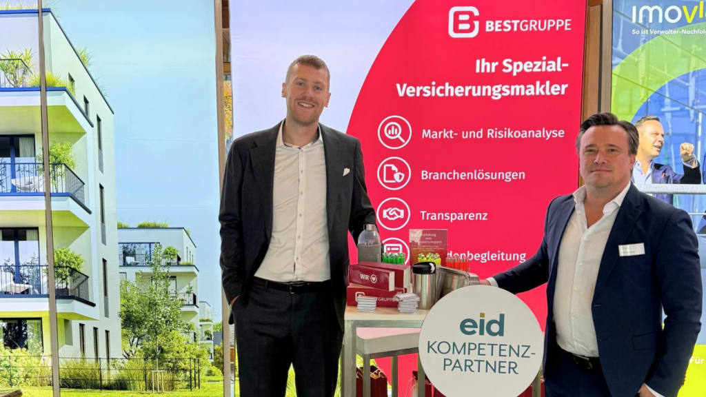 Tom Brinkmann und Andreas Hansen lächeln freundlich in die Kamera. Im Hintergrund steht ein Messestand der BEST GRUPPE.
